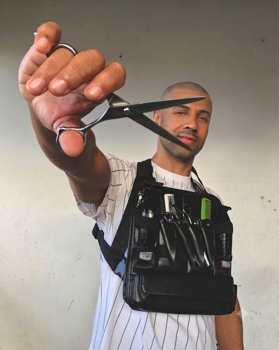 Tiago Barbeiro segurando uma tesoura, com cinto de ferramentas de barbeiro